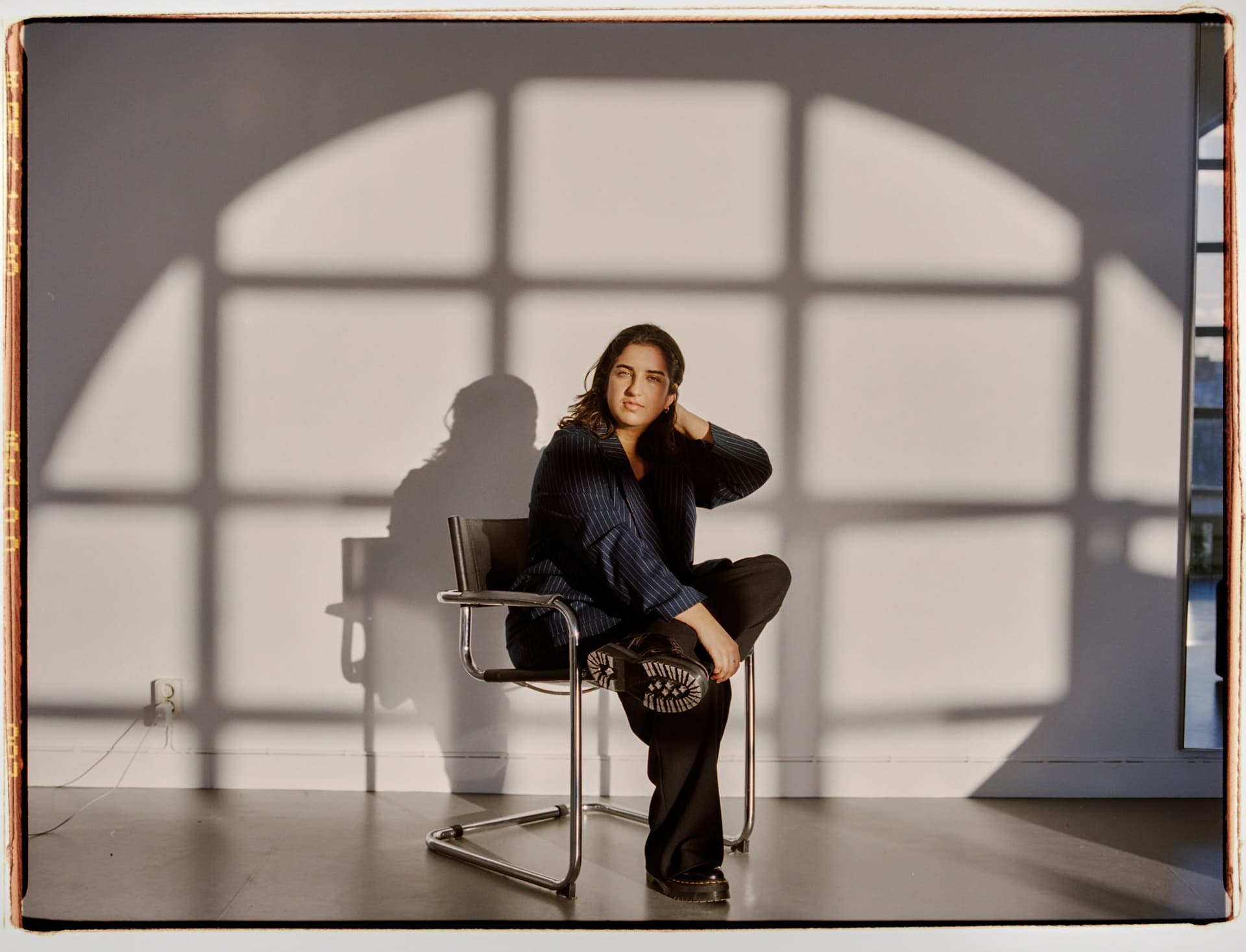 Nioosha Shams is sitting in a chair in a sunlit room